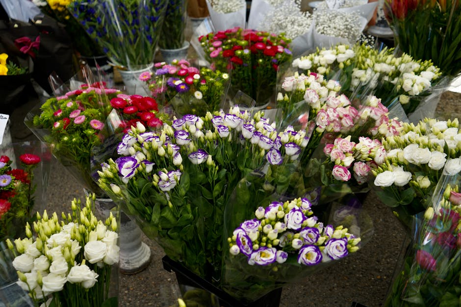 A diverse assortment of fresh floral bouquets arranged on a display table, featuring a variety of flower types, including purple and white eustoma, pink and white roses, red and pink daisies, and whit